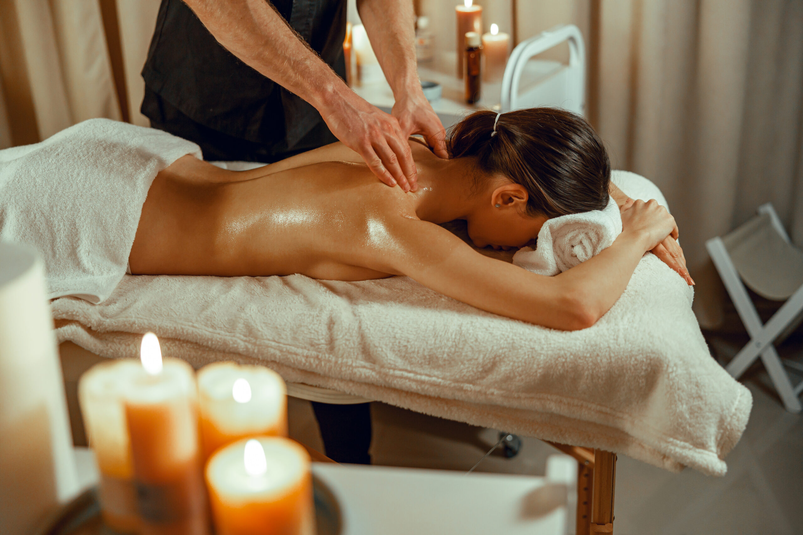 A therapist providing a shoulder and upper-back massage in a warm wellness room